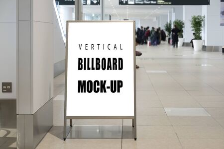 Mock up blank indoor vertical signboard with clipping path on stainless steel stand on walkway in airport terminal, empty space for insert advertising or announcement informationの写真素材