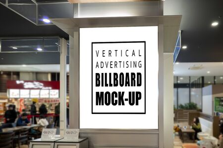 Mock up blank vertical signboard with clipping path on the pole at food court in shopping mall, empty space for insert advertising or announcement informationの写真素材
