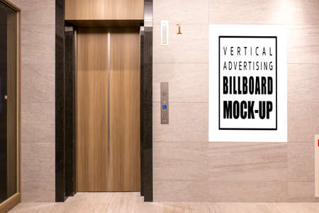 Mock up blank vertical signboard with clipping path on the wall near elevator of vintage hotel, Empty space for insert advertising graphic design or announcement and informationの写真素材