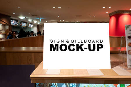 Mock up blank signboard tens  placed on wooden counter at food court, blurred people in background, empty space for insert text for announcement or information promotionの写真素材