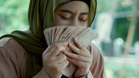 Close-up shot, the happily woman's face was Kiss on Thai money with excitement and proud of herself.の写真素材