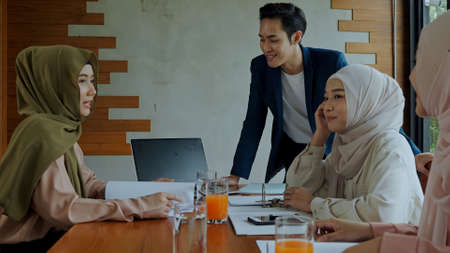 Selective focus, young handsome muslim leader man standing and talking with colleagues or his teamwork in meeting roomの写真素材