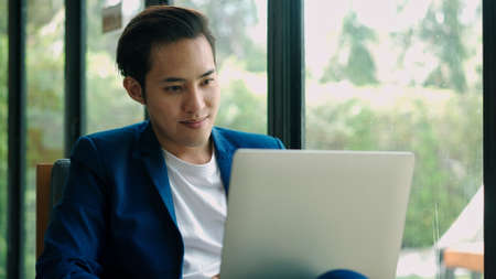 Close up portrait, young handsome muslim man sitting in coffee shop, he smiling during use laptop to working  with happinessの写真素材