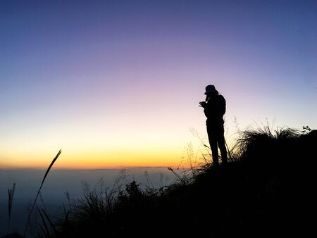 sitluate picture a woman standing on a hill With the sun in the evening.