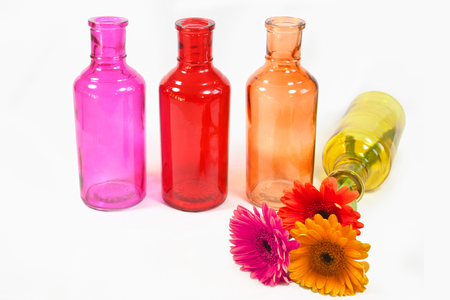 colorful gerbera flowers in colorful bottles isolated on white backgroundの写真素材