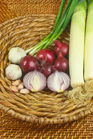 onions, garlic, leek and spring onions in a basketの写真素材