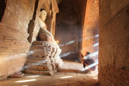 BAGAN, MYANMAR : Southeast Asian neophyte praying with candle light in a Buddihist temple in Bagan, Myanmar.のeditorial素材