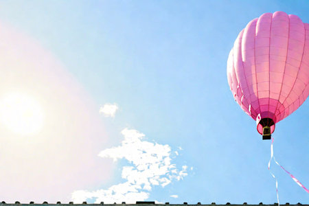 Pink hot air balloon in the blue sky with white clouds and sunの素材