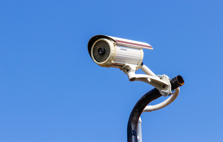Security CCTV camera on blue sky background.