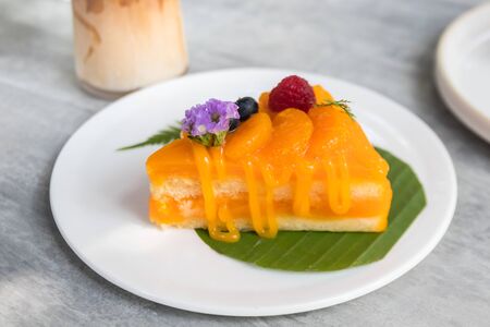 A piece of orange cake topped with orange and berries.の写真素材