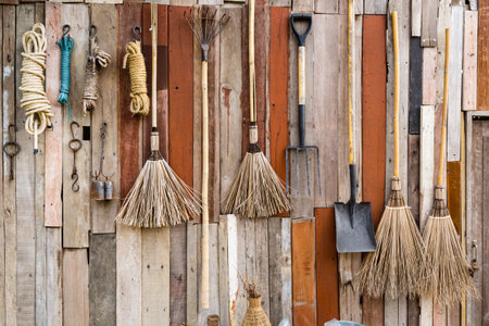 Rustic Farmhouse Wall Art , Vintage brooms and garden tools hanging on wood wall.の写真素材