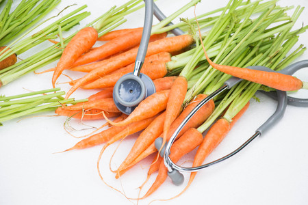 The concept of a healthy lifestyle,  carrots and stethoscope isolated on white backgroundの写真素材