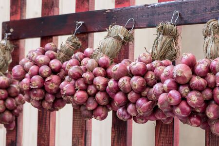 Shallot bunch hanging on a wooden wallの写真素材