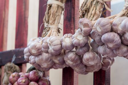 Shallot bunch hanging on a wooden wallの写真素材