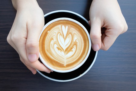 hands holding cup of coffee in coffee shop