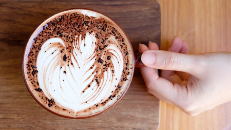 hands holding cup of coffee in coffee shopの写真素材