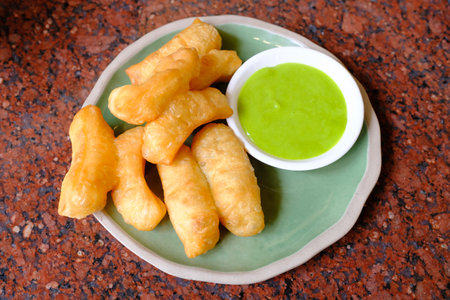 deep-fried dough stick with pandan thai custard on the red tableの写真素材