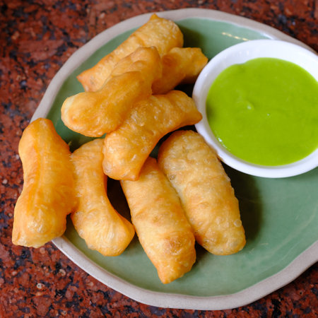 deep-fried dough stick with pandan thai custard on the red tableの写真素材