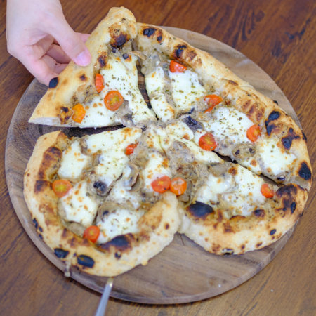 Woman taking slice of homemade  pizza at wood table, top viewの写真素材