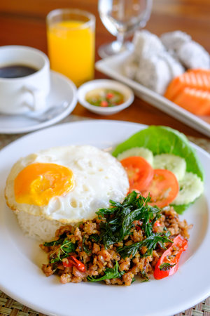 Stir Fried Basil with Pork and a fried egg on the tableの写真素材