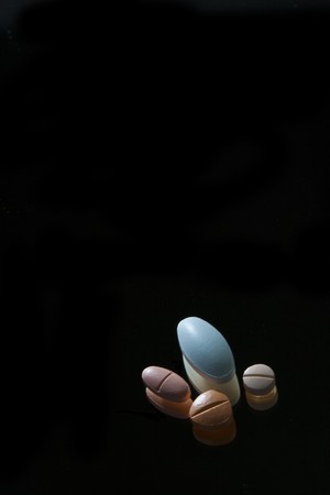Pills of different size on black background の写真素材