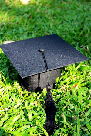 Graduation cap on green grassの写真素材