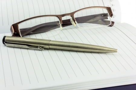 Notebook glasses and pen  isolated on white background の写真素材