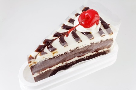 Piece of chocolate cake with cherry on white background.の写真素材