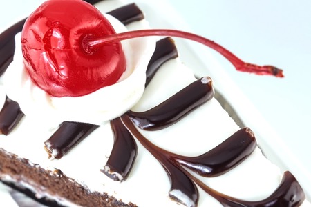 Piece of chocolate cake with cherry on white background.の写真素材