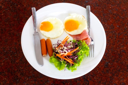 English breakfast with fried eggs, bacon, sausages, and fresh salad 