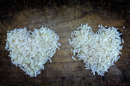 Rice grains form of heart on a wooden background.の写真素材