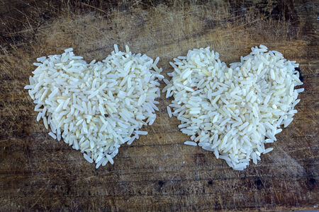Rice grains form of heart on a wooden background.の写真素材