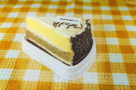 Piece of chocolate cake with cherry on yellow plaid tableclothの写真素材