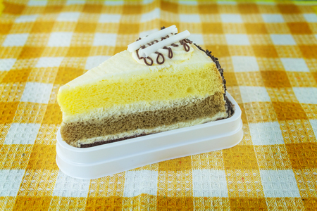 Piece of chocolate cake with cherry on yellow plaid tableclothの写真素材