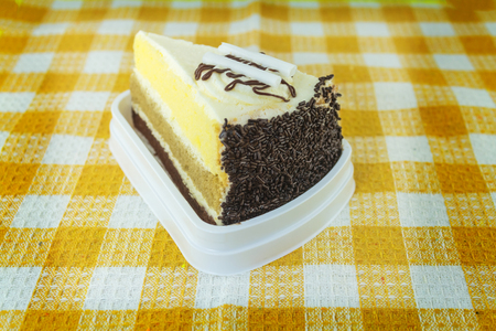 Piece of chocolate cake with cherry on yellow plaid tableclothの写真素材