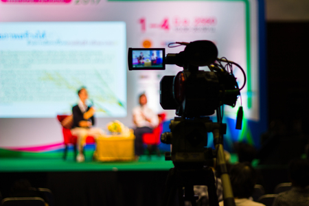 Television Camera Broadcasting an event on stage in business conference room recording participants and speakerの写真素材