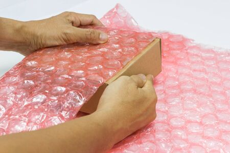hand of man hold Bubbles covering the box by plastic wrap for protection product cracked  or insurance During transit -isolated white backgroundの写真素材