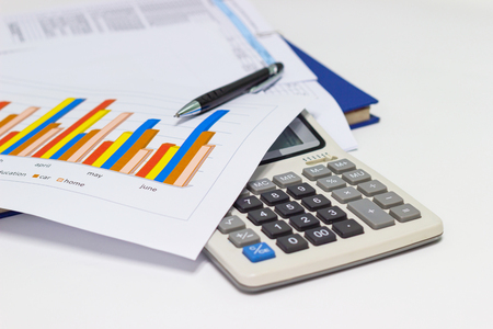 business paper graphs and pen with charts report, calculator on desk of financial planning, concepts business and cost.の写真素材