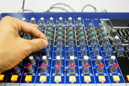Men's hands are controlling the console of a large hi-fi system. Sound equipment. Control panel of a digital studio close-up mixer.の写真素材