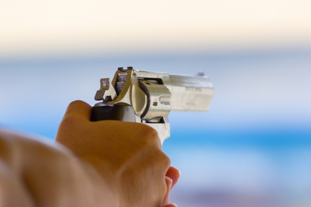 Hand of men hold a gun ready to shoot  practicing shooting in the park selective focus on the back part of gunの写真素材