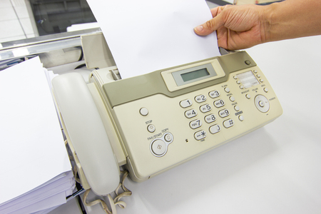 Hand man are using a fax machine send paper in the office Business conceptの写真素材