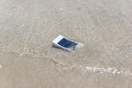 White Mobile phone floated to the sea at the beach.の写真素材