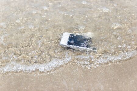 White Mobile phone floated to the sea at the beach.の写真素材
