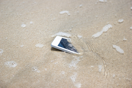 White Mobile phone floated to the sea at the beach.の写真素材
