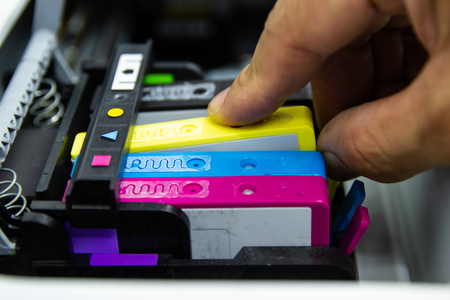 Close up hand man put the color printer ink jet cartridge of the printer inject