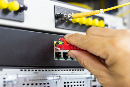 Hand of man holding The network cables to connect Lan port in the Datacenter room, concept...