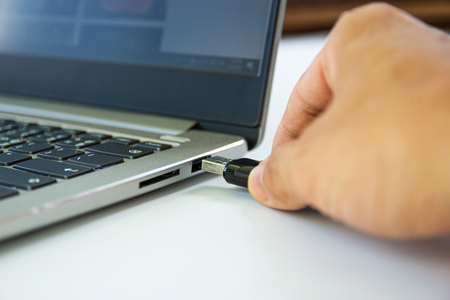 hand man connect flash drive to USB port plug-in computer laptop for transfer data and backup business conceptの写真素材