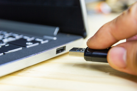 hand man hold Flash drive connect to USB port plug-in computer laptop for transfer data and backup...