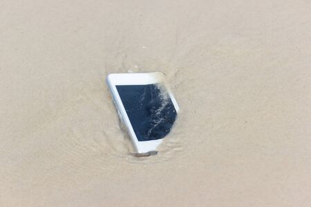 White Mobile phone floated to the sea at the beach.の写真素材