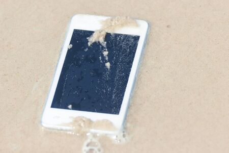 White Mobile phone floated to the sea at the beach.の写真素材